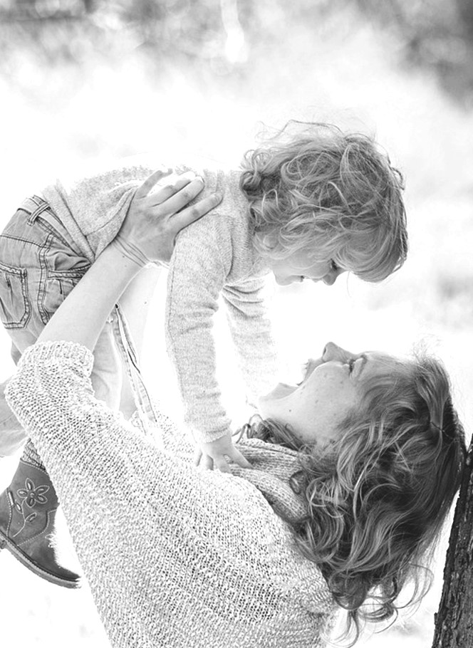 Lachende Mutter hält strahlende Tochter in den Armen