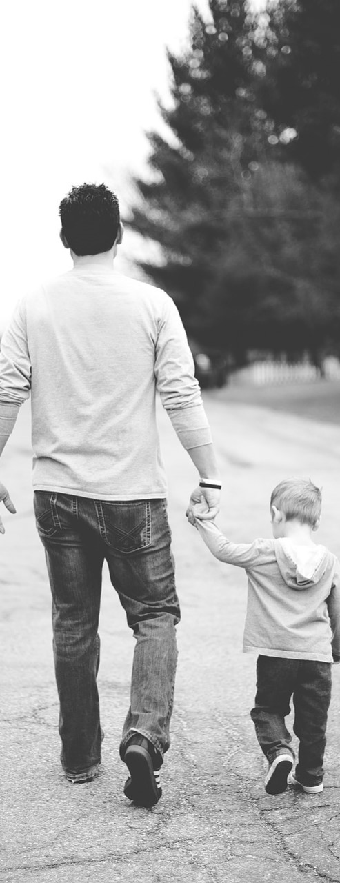 Vater und Sohn gehen Hand in Hand eine Straße entlang